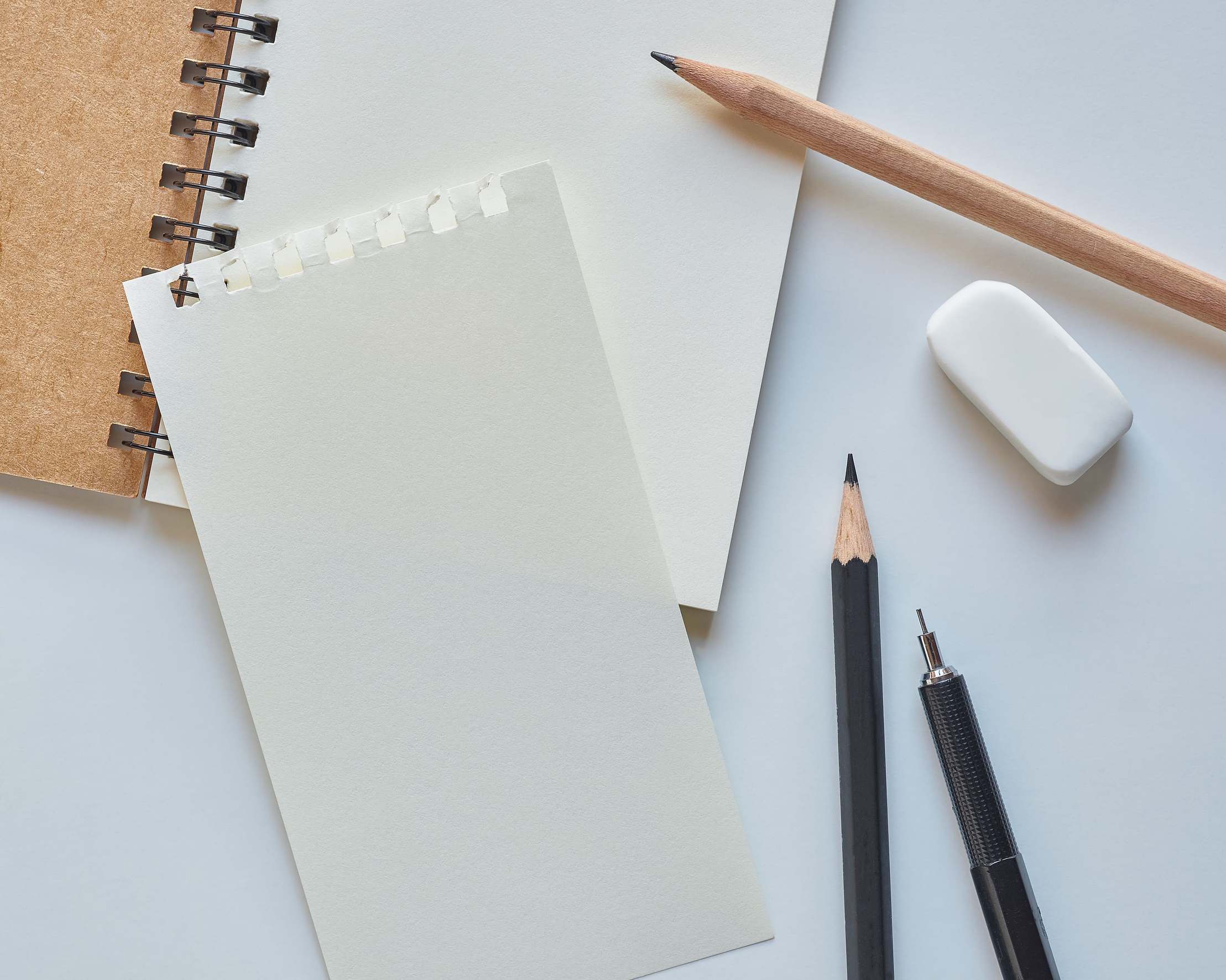 Overhead view of notes and pens on a desk with a spiral notebook